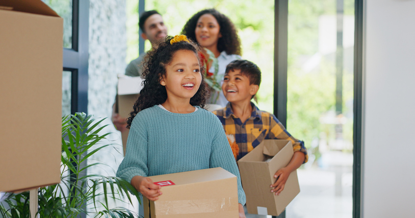 famille avec des enfats portant des cartons de déménagement.