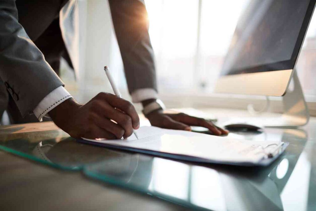 homme qui tient un stylo dans la main droite et qui signe un contrat