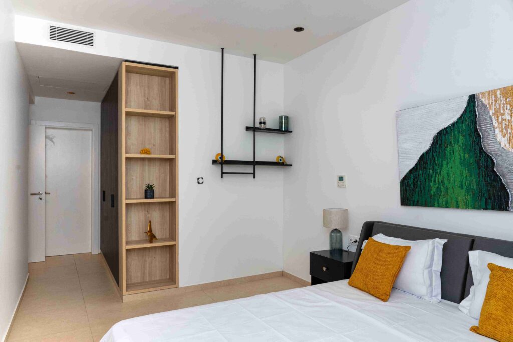 Chambre témoin moderne avec étagères bois et coussins jaunes